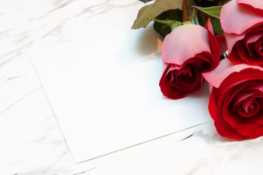three roses and a blank sheet of paper on a marble surface