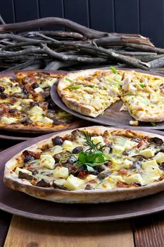  Three pizzas laid out on wooden trays on a wooden tables in a pizzeria.