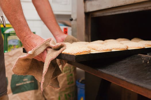 Taking out a tray of pastry from the oven in a bakery