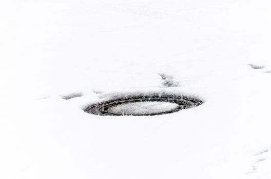 Manhole covers after snowfall covered by snow.