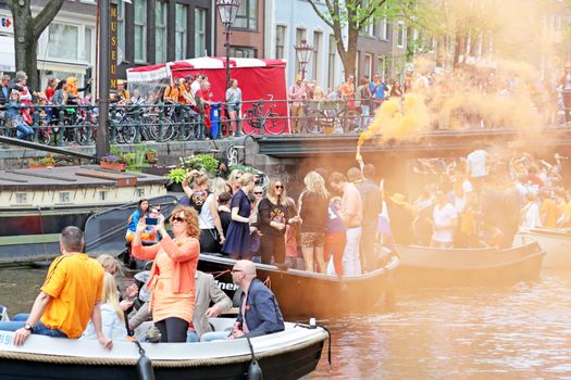 AMSTERDAM - APRIL 26: Amsterdam canals full of boats and people in orange during the celebration of kings day on April 26, 2014 in Amsterdam, The Netherlands