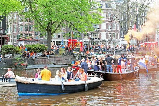 AMSTERDAM - APRIL 26: Canals of Amsterdam full of people in orange on boats during the celebration of kings day on April 26, 2014 in Amsterdam, The Netherlands
