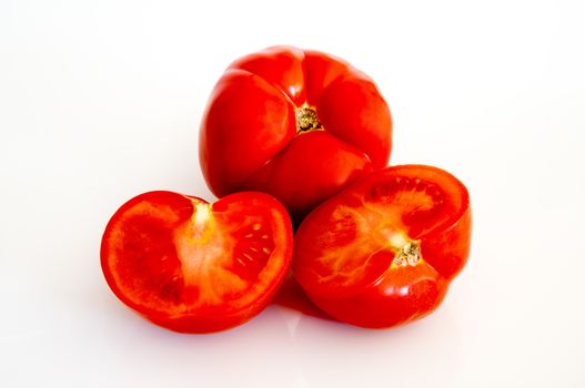 three beautiful tomatoes to rest upon white background