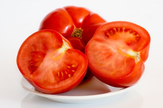 three tomatoes lies in plate on white background