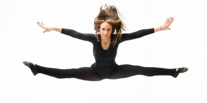 beautiful caucasian female dancer jumping and doing split up in the air, on white background