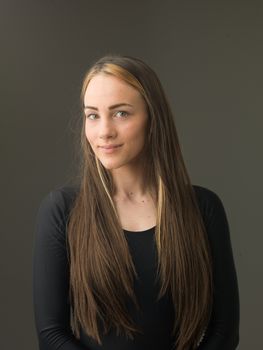 portrait of beautiful young woman with long blond hair, on grey background