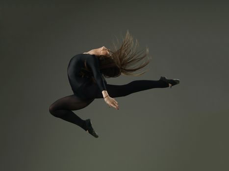 dancer performing high jump against grey background