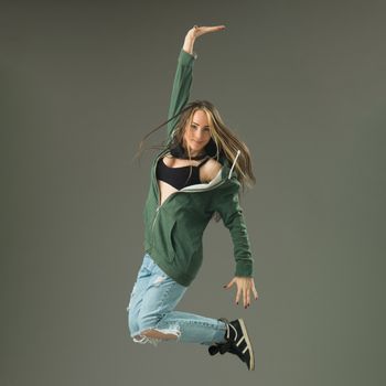 happy modern style dancer jumping against grey studio background