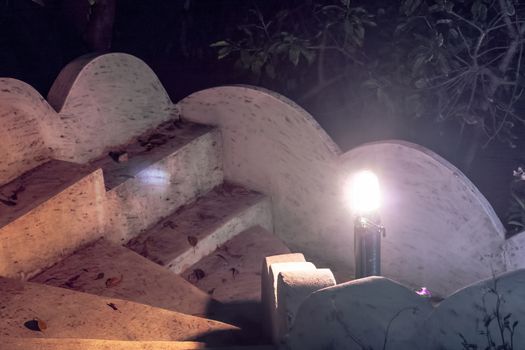 A spiral staircase going down, photographed from above at night and illuminated by a single light source - a lantern.