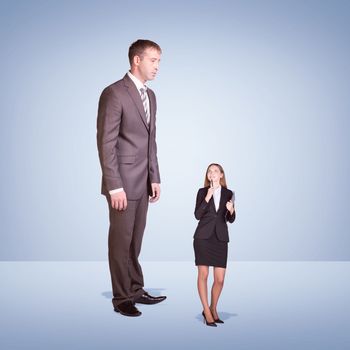 High businessman looking down at little woman with pen and clipboard. Clouds and cement surface as background. Business concept