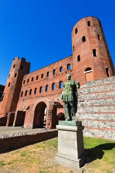 Roman statue of Julius Caesar and ancient ruins of Palatine Towers in Torino, Piemonte, Italy