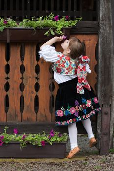 Little girl in traditional costume smell the flower