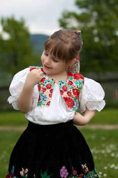 Little girl in costume on meadow, holding butterfly