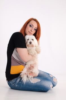 Young redhead woman with her white Maltese dog in studio