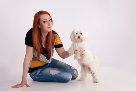 Young redhead woman with her white Maltese dog in studio