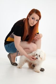 Young redhead woman with her white Maltese dog in studio