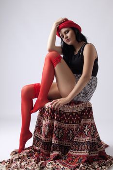 Young long-haired woman with red hat sitting thoughtfully on chair