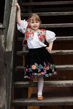Little girl in traditional costume standing on the stairs