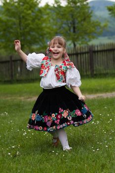 Little girl in costume running around the meadow with flowers