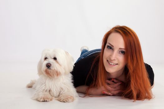 Young redhead woman with her white Maltese dog in studio