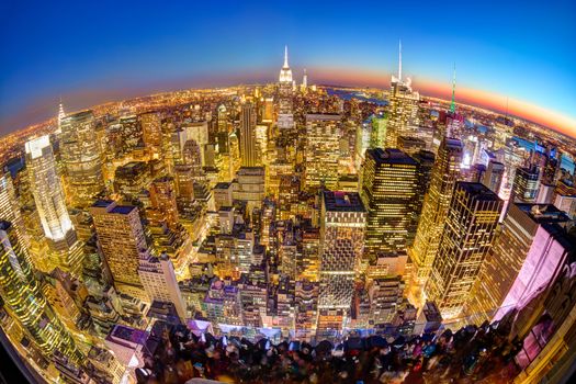 New York City. Manhattan downtown skyline with illuminated Empire State Building and skyscrapers at dusk seen from Top of the Rock observation deck. Vertical composition Fish eye lens shot.