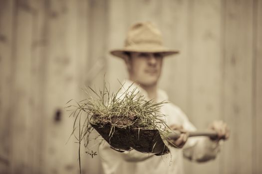 Farmer with a Shovel Full of Grass. Focus on the Grass