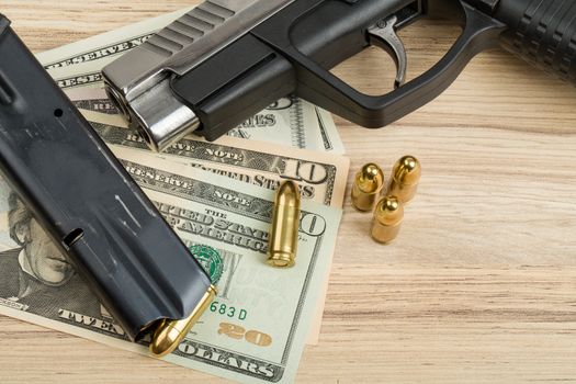 detail of gun with bullet on US dollar banknotes, crime or corruption concept