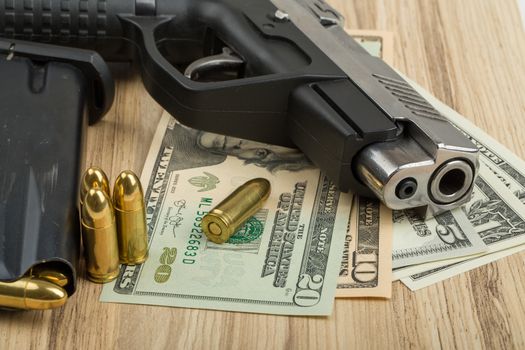 detail of gun with bullet on US dollar banknotes, crime or corruption concept