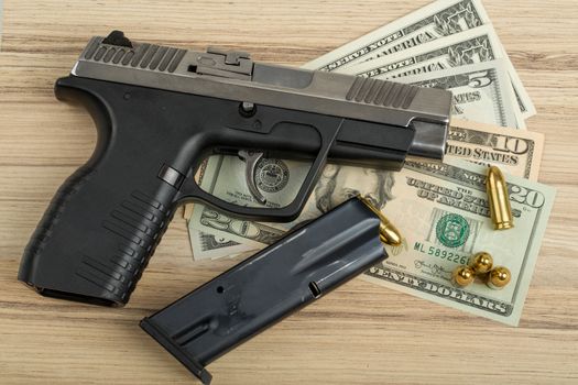detail of gun with bullet on US dollar banknotes, crime or corruption concept