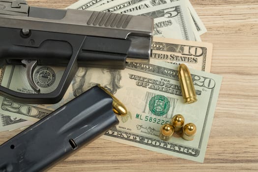 detail of gun with bullet on US dollar banknotes, crime or corruption concept