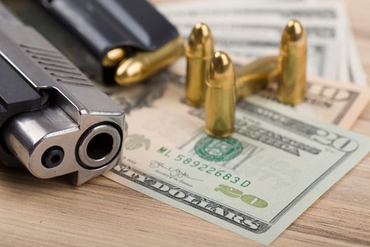 detail of gun with bullet on US dollar banknotes, crime or corruption concept