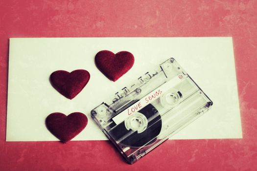 Audio cassette tape on red backgound with fabric heart, Valentine postcard. Love concept with evelope in vintage tone color