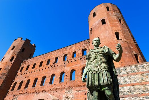 Roman statue of Julius Caesar and ancient ruins of Palatine Towers in Torino, Piemonte, Italy