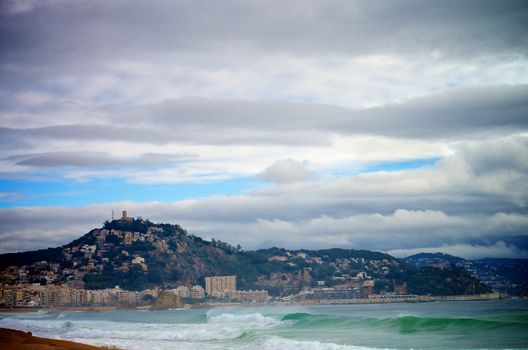 Stormy Coast and View on Castle of San Juan Mountain on Dramatic Sky background, Blanes, Spain