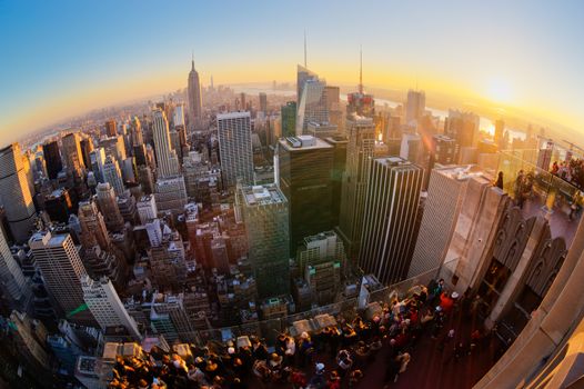 New York City. Manhattan downtown skyline with illuminated Empire State Building and skyscrapers at sunset seen from Top of the Rock observation deck. Vertical composition Fish eye lens shot.