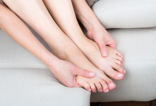 Woman sitting on sofa, close up view of legs and hands