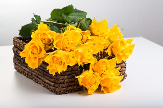 Beautiful bouquet of roses in basket on white background