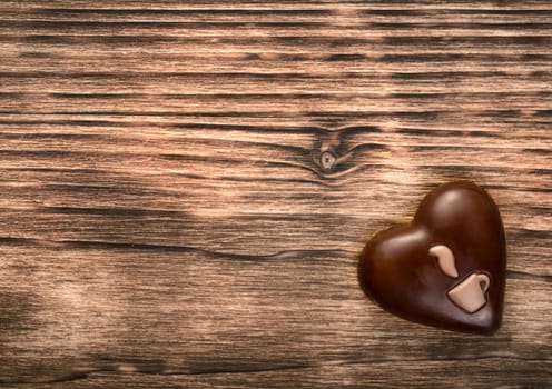 Sweet chocolate heart with coffee cup shape on wooden background