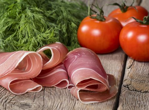 Ham with tomatoes and herb on wooden background