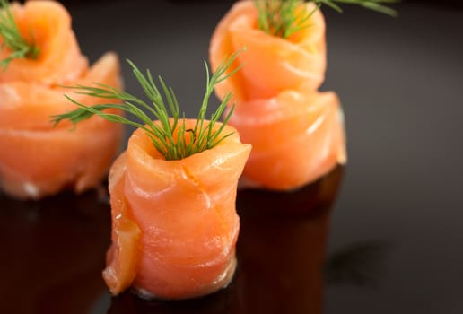Salmon rolls on black glass plate