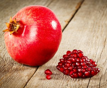 Whole pomegranate with seeds on wooden background