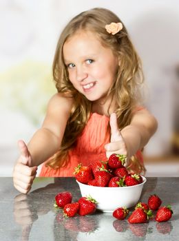 Little girl with strawberry at the table