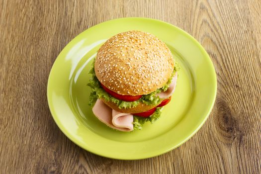 Burger on green plate on wooden table