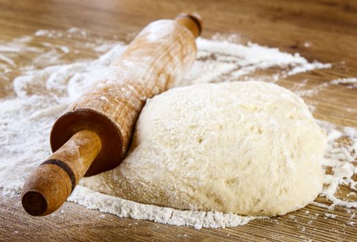 Dough with rolling pin on wooden table