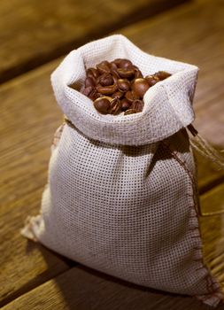 Coffee beans in burlap bag on wooden background