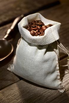 Coffee beans in the burlap sack on wooden table