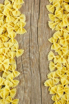 Raw farfalle pasta on wooden background