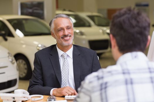 Salesman speaking with a client at new car showroom