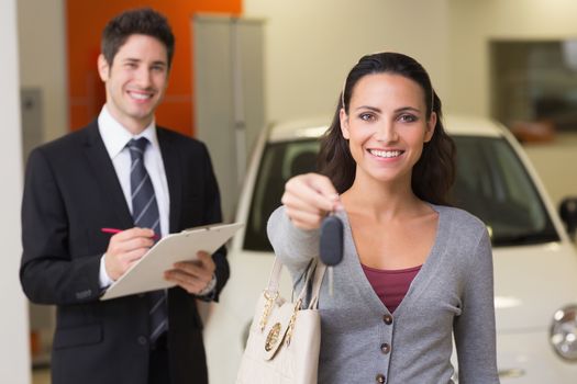 Happy customer holding a car key at new car showroom