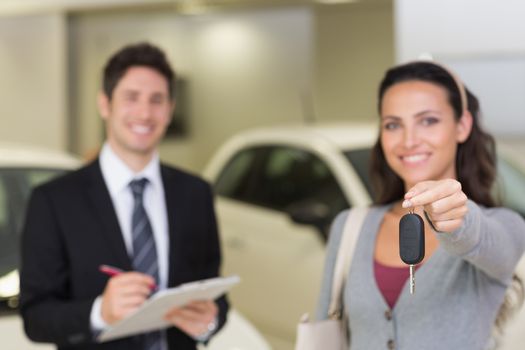 Female driver showing a key after bying a new car at new car showroom